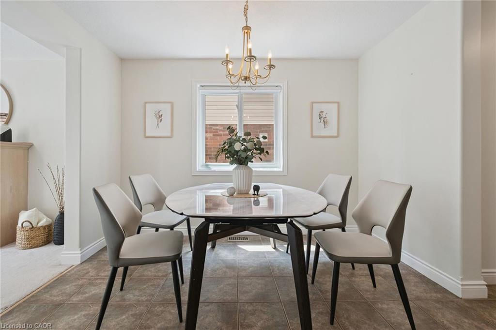 Dining area featuring a central window, warm-toned tile flooring, and a brass-finish chandelier