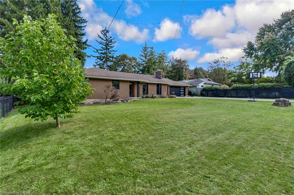 Expansive lawn with mature trees and a fenced perimeter