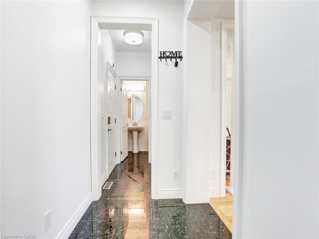 Hallway featuring dark, reflective floor tiling, white baseboards, and a white interior door with decorative glass inserts
