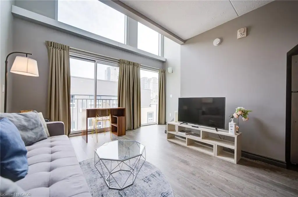 Living area featuring high ceilings, wood-finish flooring, and expansive floor-to-ceiling windows with upper transoms