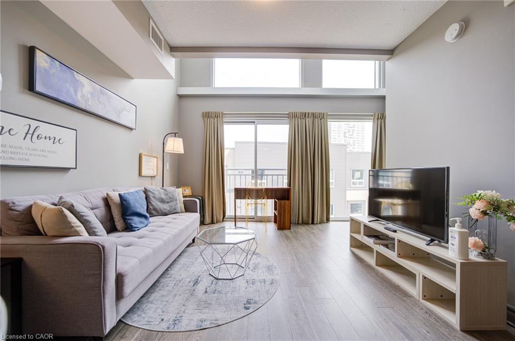 Living area featuring high ceilings, wood-finish flooring, and a sliding glass door to a balcony