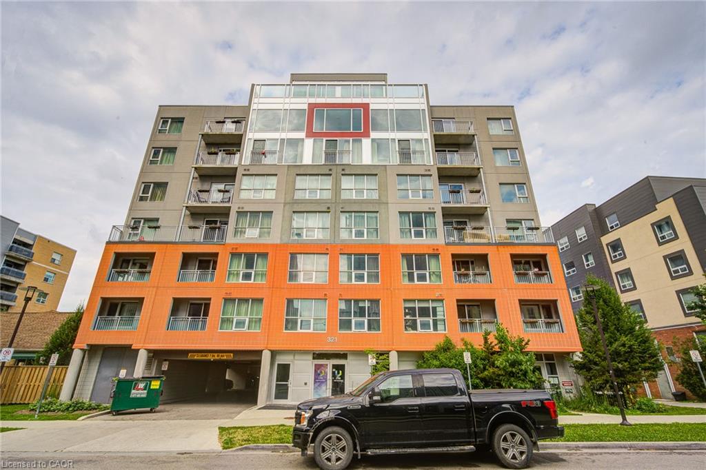 Modern multi-story building featuring a facade with orange and gray panels, multiple balconies, and an integrated ground-level parking garage