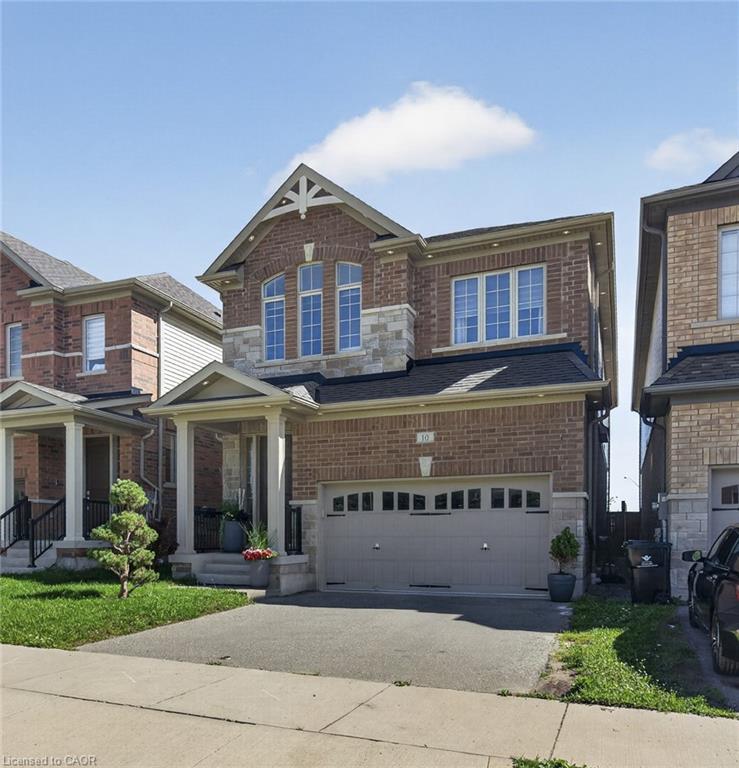 Brick and stone facade, covered front porch, arched window detailing, asphalt driveway, and an attached two-car garage
