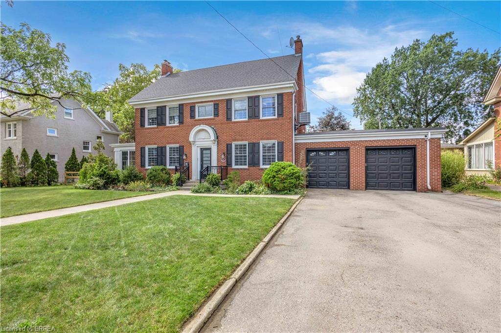 Red brick exterior with black shutters, arched entryway, a double garage, and a lush front lawn
