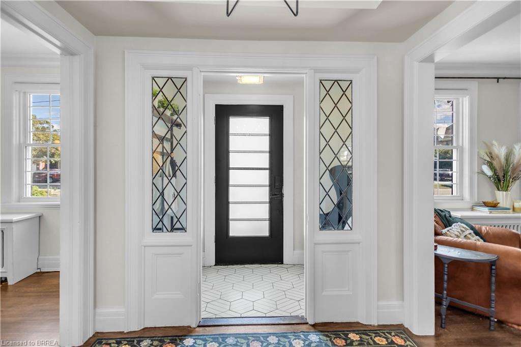 Foyer with hexagonal tile flooring, decorative glass sidelights, and a paneled entry door with frosted glass inserts