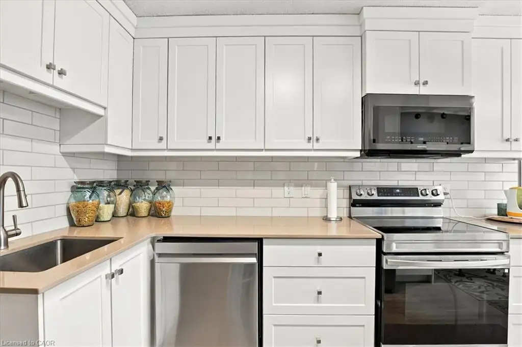 White shaker cabinetry, light-toned countertops, stainless steel appliances, undermount sink, and subway tile backsplash