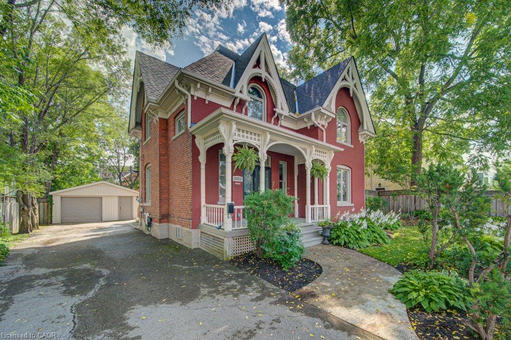 Brick-and-stucco Victorian exterior with ornate white trim, arched windows, and a covered front porch