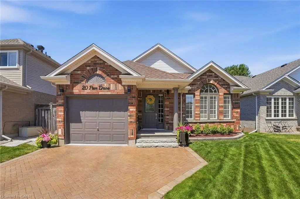 Brick facade residence featuring a single-car garage, arched entry window, stone steps, a covered porch with a column, and a paver driveway