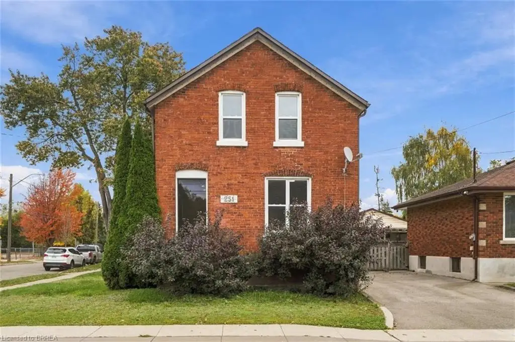 Two-story red brick exterior featuring a gable roofline, white-trimmed rectangular windows, and a paved private driveway