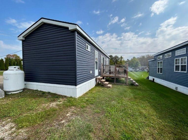 View of side of home featuring a yard and a wooden deck