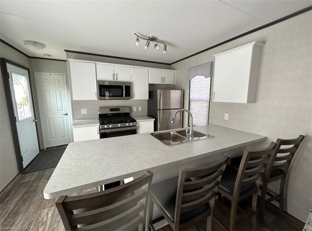 Kitchen with a breakfast bar area, crown molding, a peninsula, stainless steel appliances, and light countertops