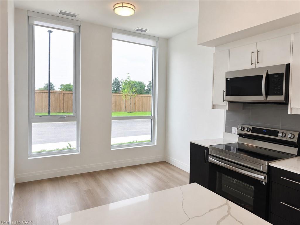 Contemporary kitchen featuring two-tone cabinetry, stainless steel appliances, and a quartz countertop island