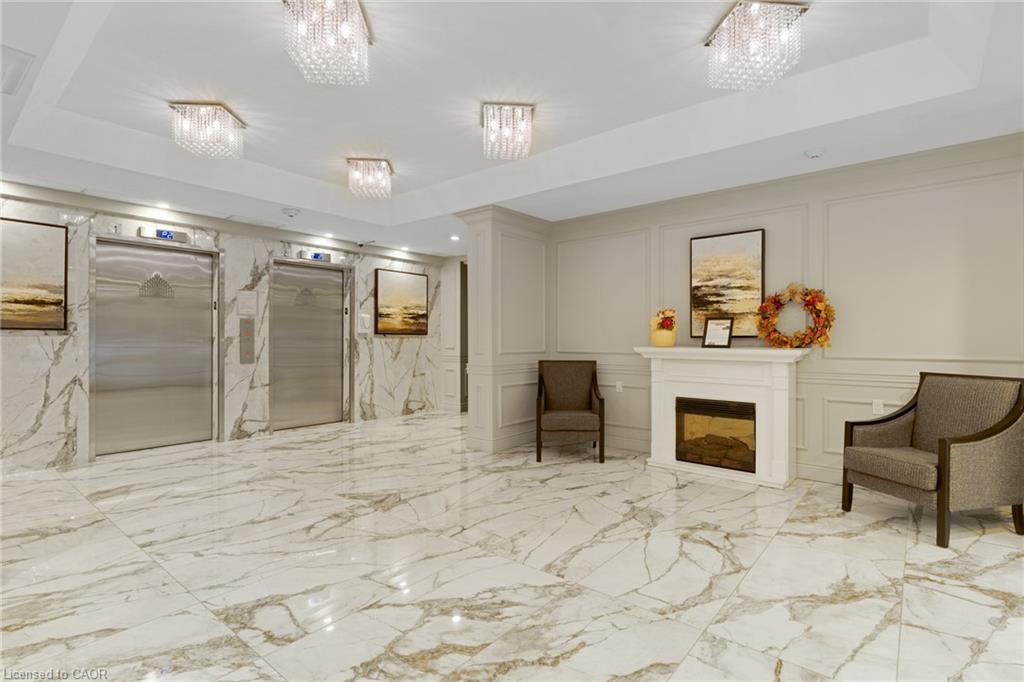 Polished tile flooring, stainless steel elevator doors, elegant wall paneling, decorative fireplace, and recessed lighting