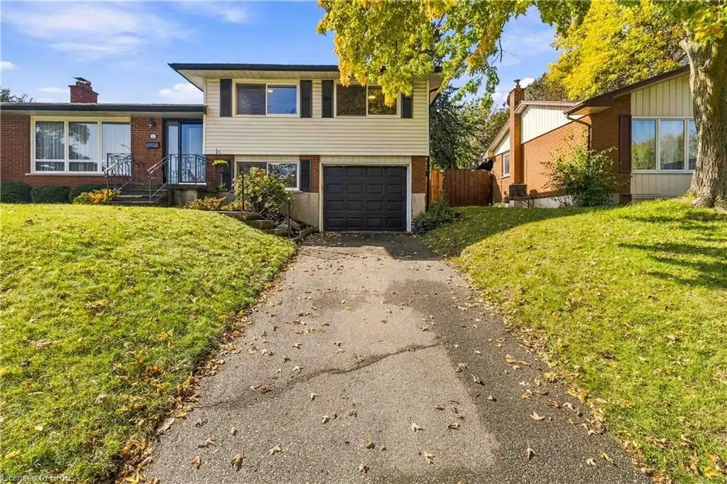 Split-level exterior featuring a brick and siding facade, an attached single-car garage, and an asphalt driveway