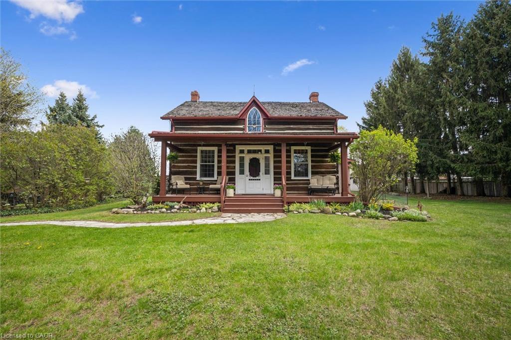 Log cabin exterior with a covered front porch, white-trimmed windows, and a central white entry door