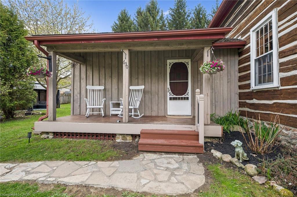 Covered front porch with wood plank siding, a decorative screen door, and a stone walkway
