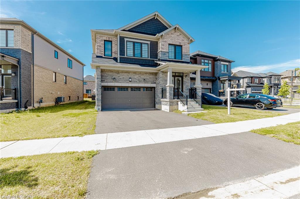 Stone and siding exterior with dark trim windows, covered front entrance, and an attached two-car garage