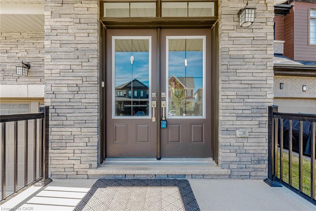 Stone veneer facade with dual entry doors, transom window, and exterior wall lanterns