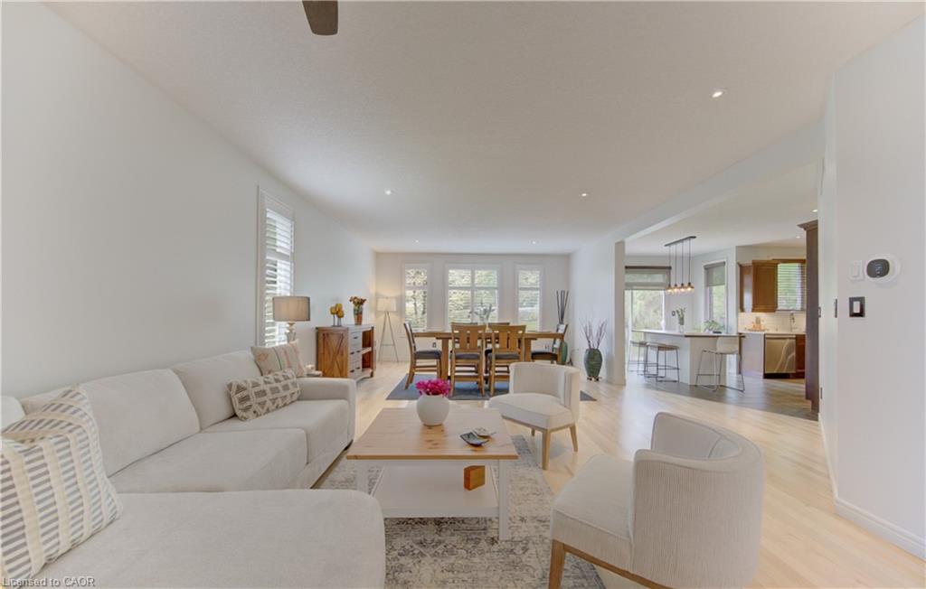 Expansive living space featuring light wood-finish flooring, recessed lighting, white window shutters, and an open layout to the dining area and kitchen