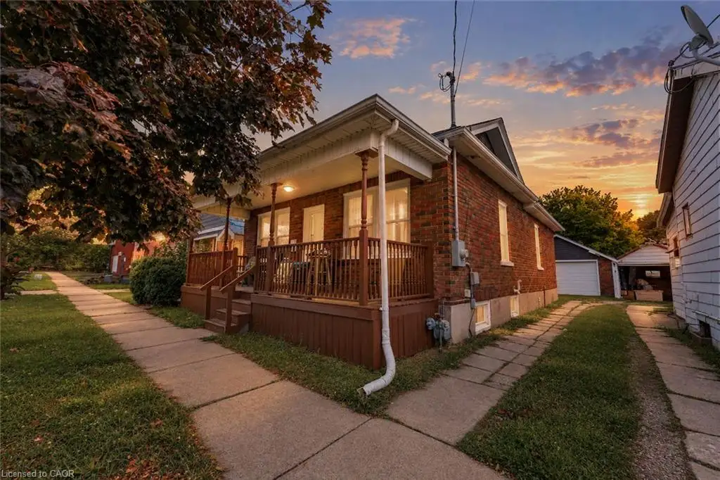 Brick exterior with covered front porch, wood railing, and concrete walkway