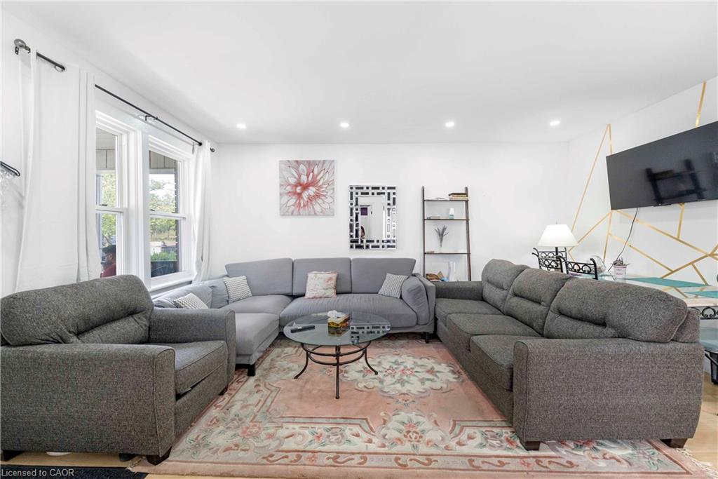 Spacious living area featuring light wood-finish flooring, recessed lighting, and ample natural light from multiple windows