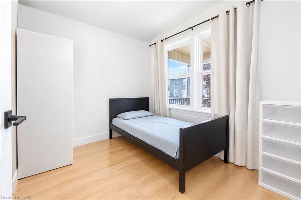 Bright room featuring a multi-pane window, wood-finish flooring, and a white interior door with matte black hardware