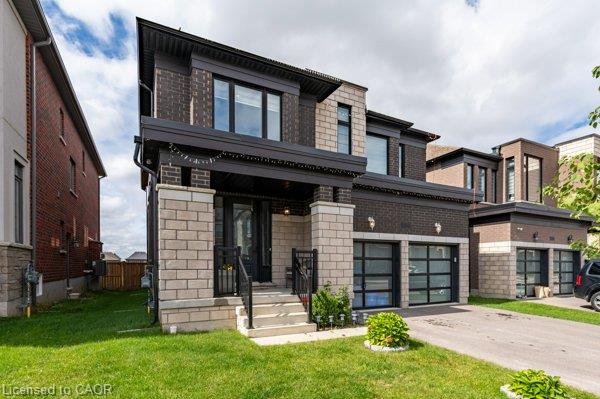Two-story facade with dark brick and light-toned stone accents, covered entry, and two garage doors with frosted glass panels
