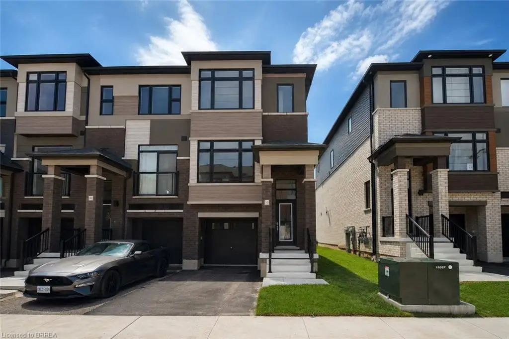 Contemporary townhome with a multi-level facade, integrated garage, paved driveway, covered entryway, and dark-framed windows