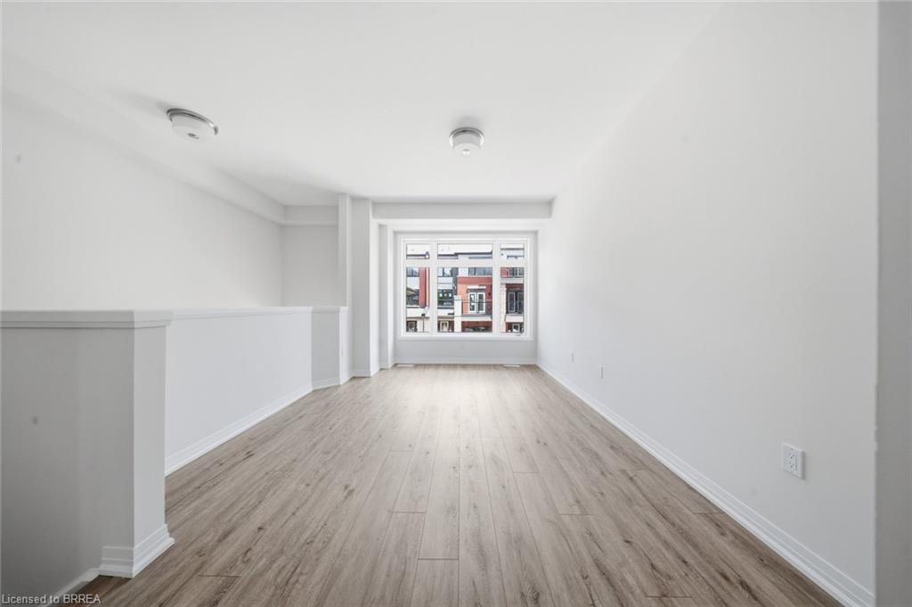 Open concept room featuring wood-finish flooring, white walls, and a large window