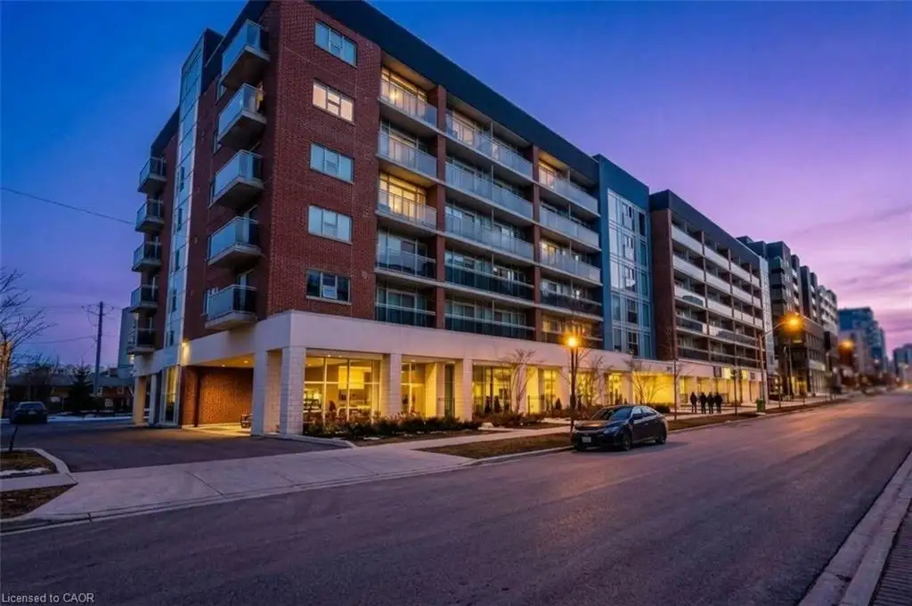 Multi-story brick exterior building featuring glass balcony railings, expansive floor-to-ceiling windows on the ground level, and recessed covered parking