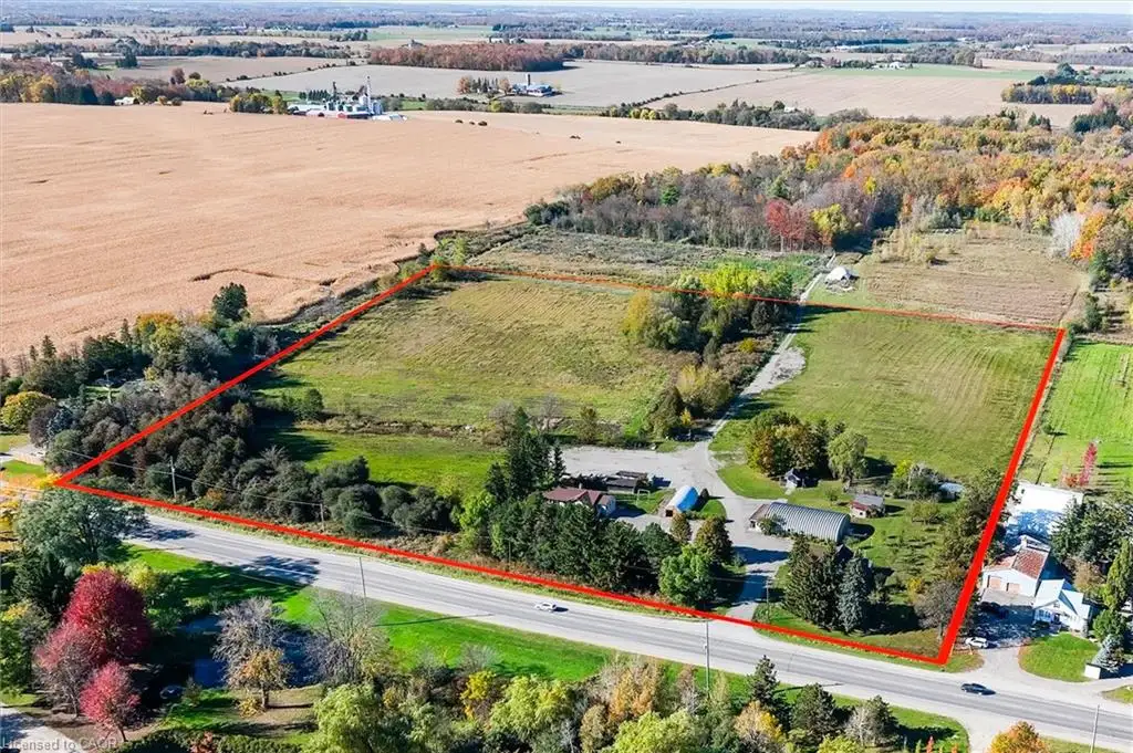 Expansive acreage featuring cleared pasture, pockets of mature trees, multiple outbuildings, and paved driveway access
