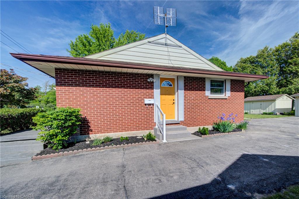 Brick exterior with light-colored siding, a brightly colored front door, and a paved driveway