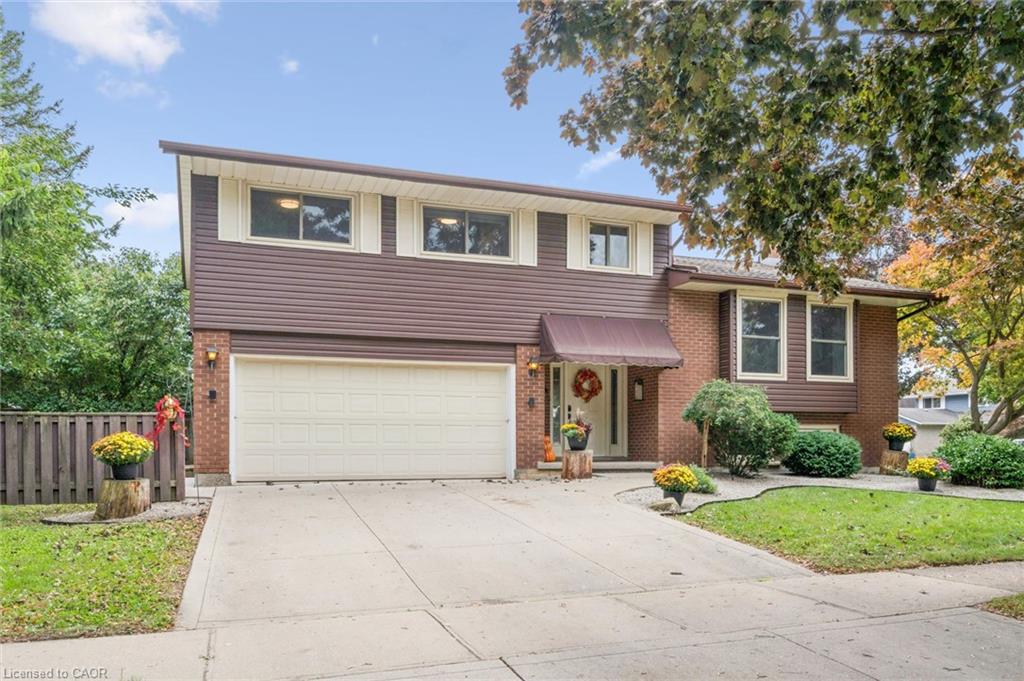 Brick and horizontal siding exterior with a two-car garage, concrete driveway, and mature landscaping