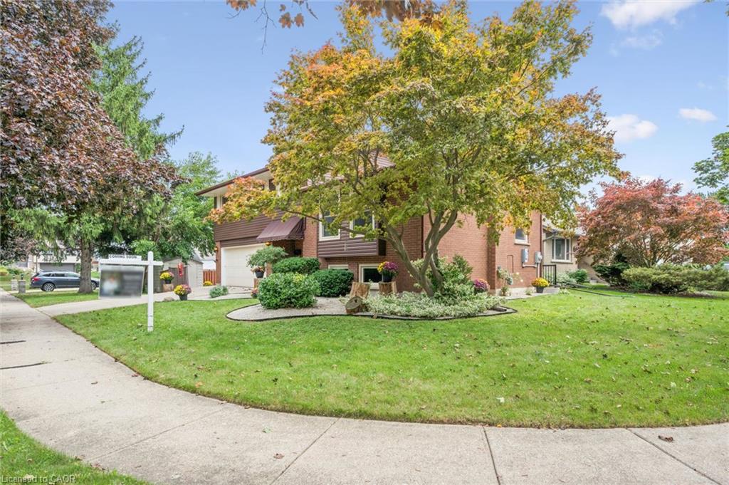 Brick exterior with wood-paneled accents, attached two-car garage, and established landscaping