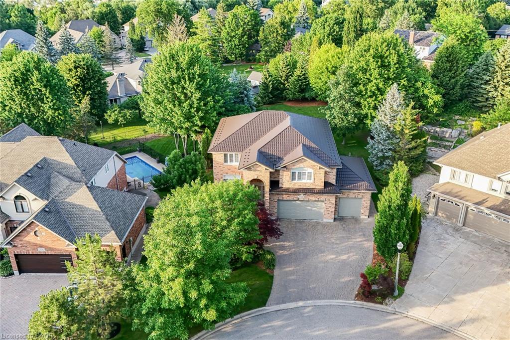 Brick facade residence featuring a multi-car garage, mature landscaping, and a substantial paved driveway