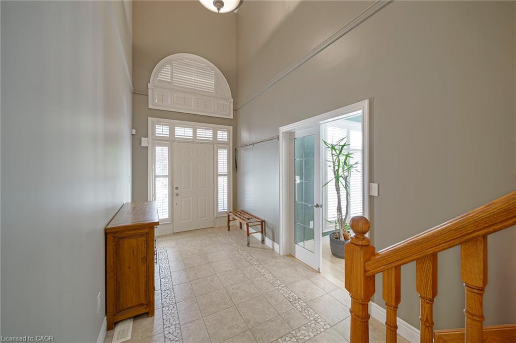 Two-story foyer with transom and sidelight windows, tile flooring with decorative inlay, and a built-in staircase featuring wood banisters