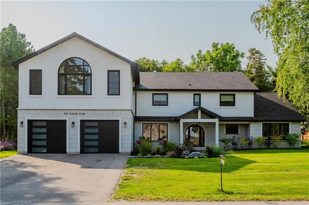Contemporary residence featuring a two-car garage with frosted glass panel doors, a prominent arched window on the upper level, and a covered entryway with a rounded door