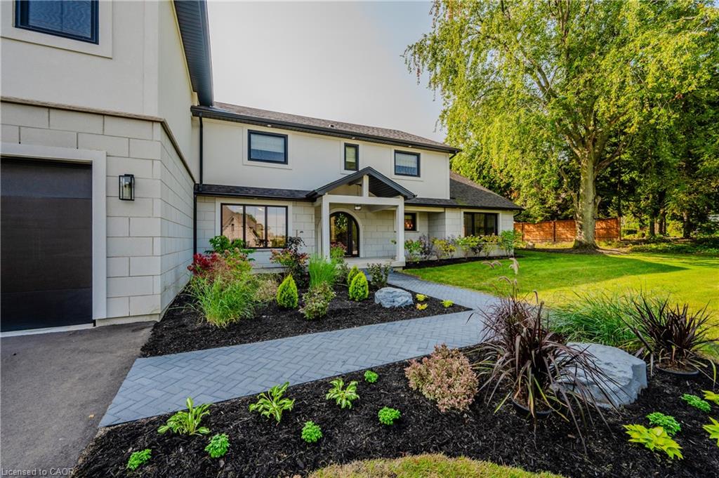 Contemporary residence featuring a stucco and stone-look exterior, black-framed windows, and a black garage door
