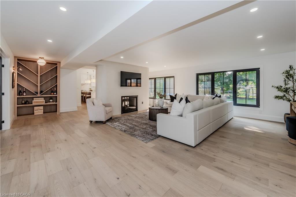 Expansive room featuring light wood-finish flooring, recessed lighting, and a built-in shelving unit with geometric detailing