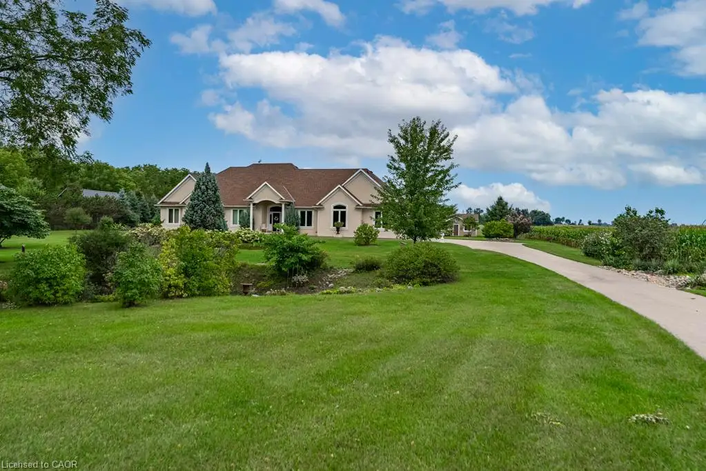 Spacious property featuring a long paved driveway, extensive green lawn, and mature trees