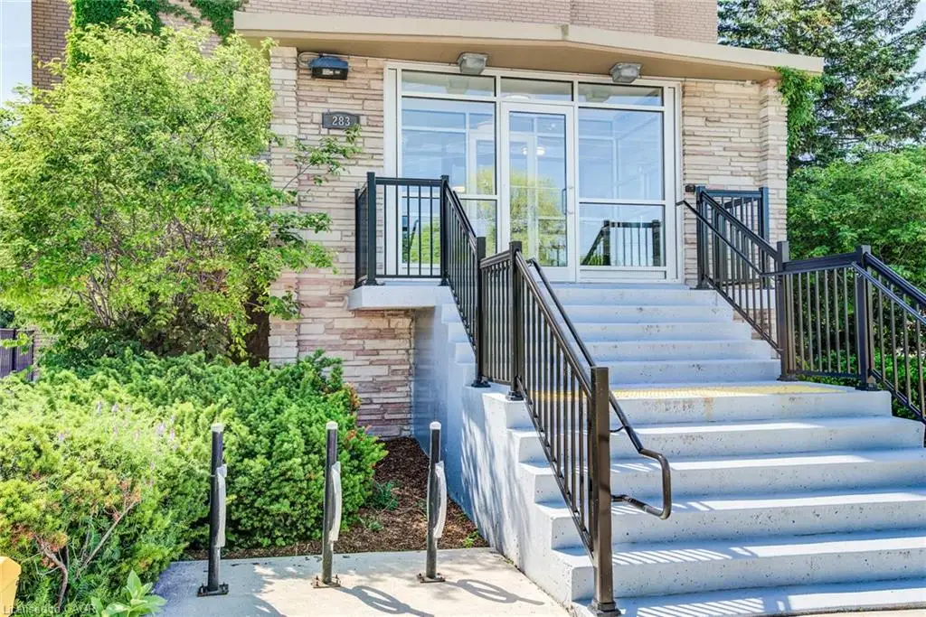 Building entrance featuring a stone facade, glass double doors, and concrete steps with black metal railings