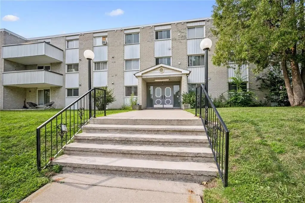 Concrete exterior with multiple balconies, a covered entrance, and mature landscaping