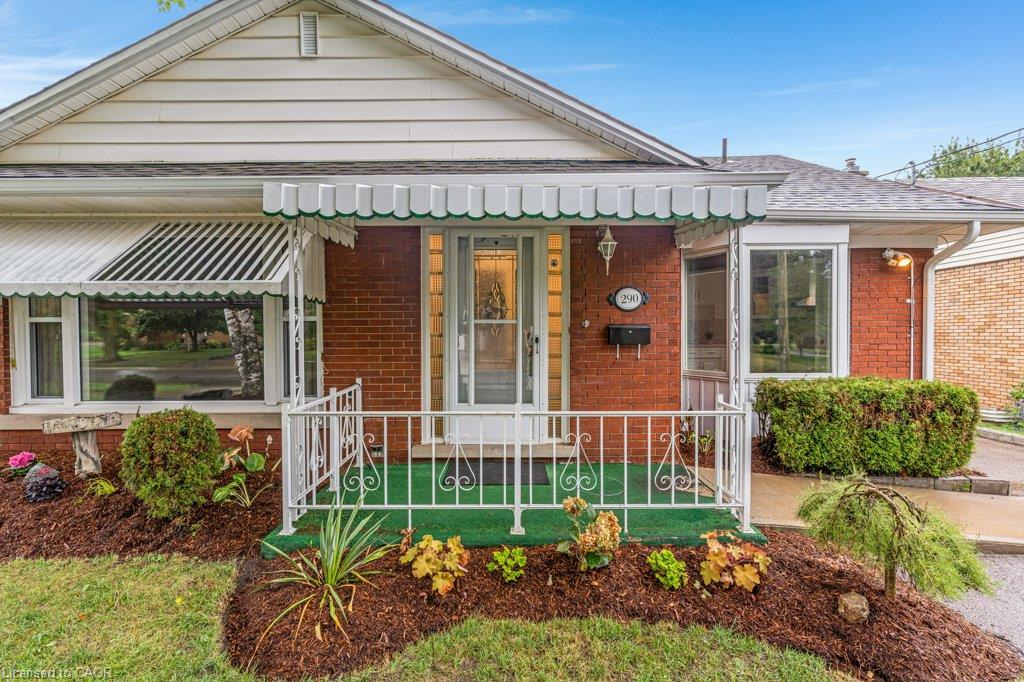 Brick exterior with white siding and a covered front porch featuring wrought iron railings