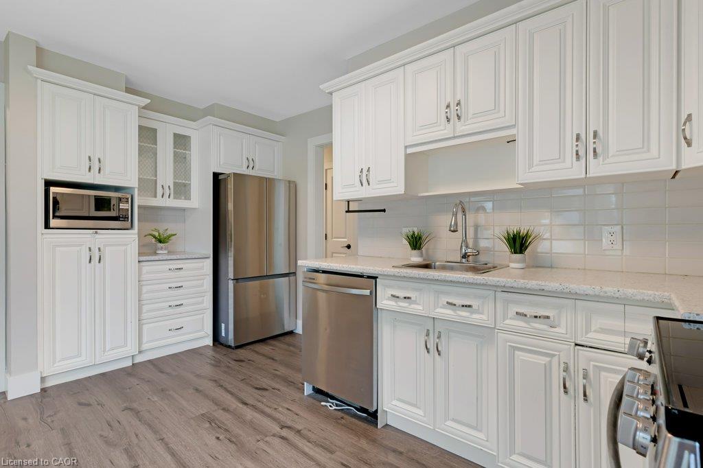 Kitchen featuring white shaker-style cabinetry, stainless steel appliances, wood-finish flooring, undermount sink, and a white subway tile backsplash