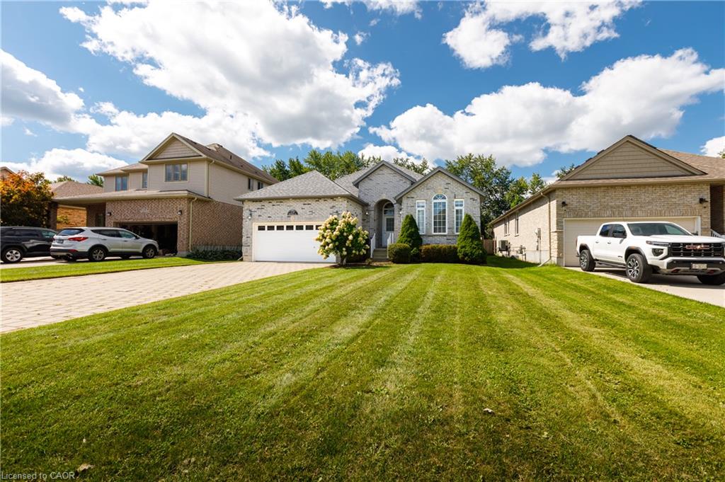 Stone facade with an arched window, a prominent single-car garage, and a paver driveway