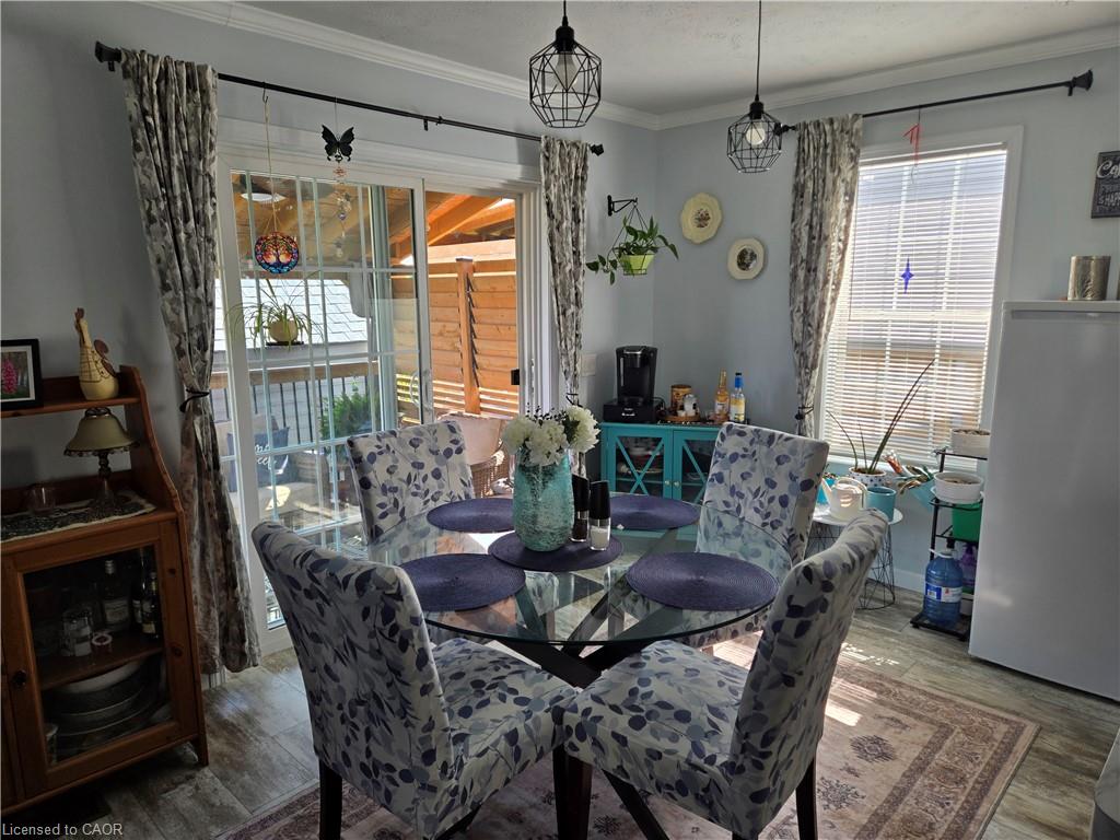 Dining area featuring wood-finish flooring, crown molding, and two pendant light fixtures