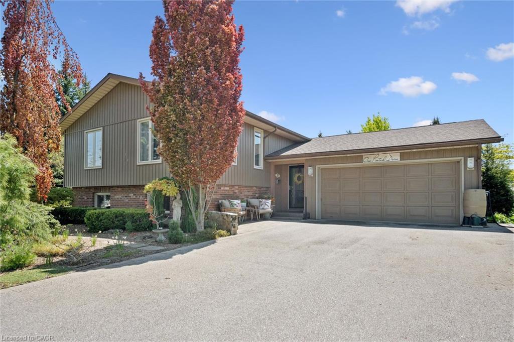Split-level home featuring a two-car garage, brick and vertical siding exterior, and a paved driveway