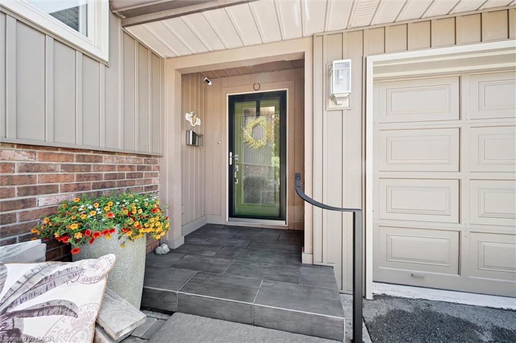 Board and batten siding, brick facade, garage door, covered entry, and dark-framed glass panel front door