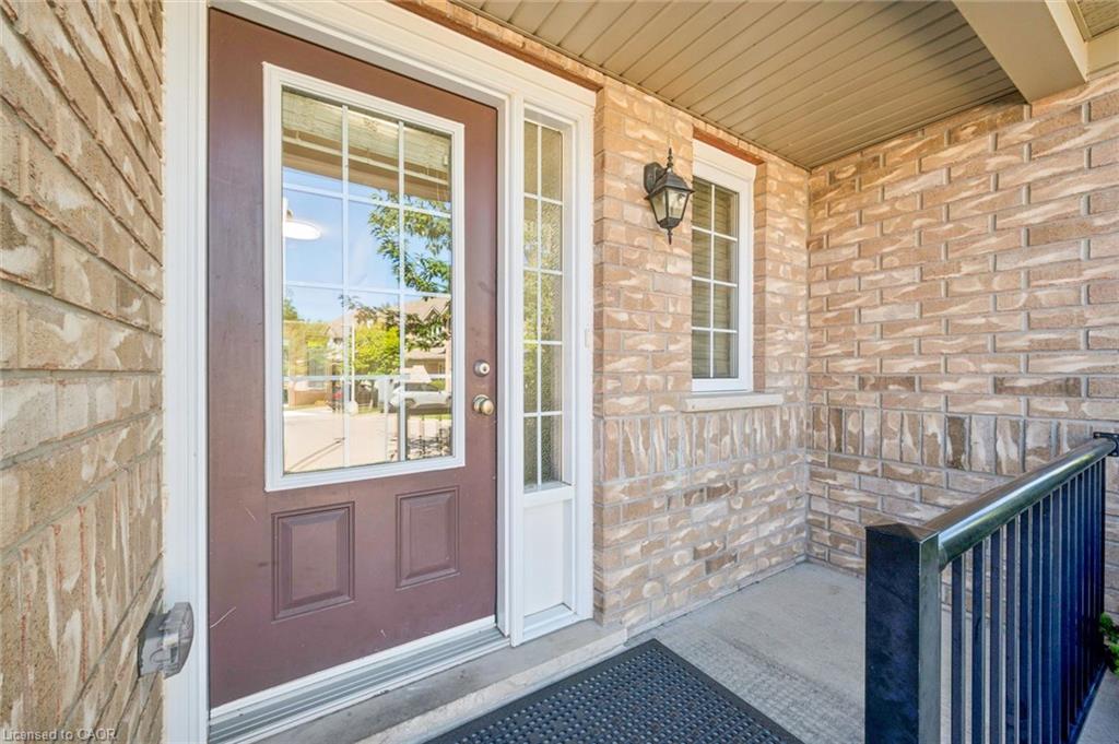 Brick exterior with covered porch, paneled entry door with divided lites, and a decorative wall-mounted light fixture