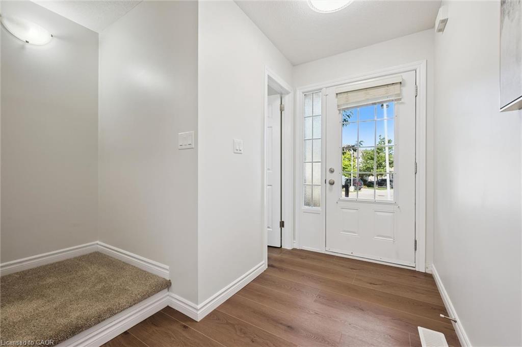 Entryway featuring wood-finish flooring, a white paneled front door with decorative glass, and a sidelight